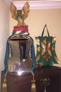 The Prior's arms and crest display on a stechhelm jousting helmet and a targe shield